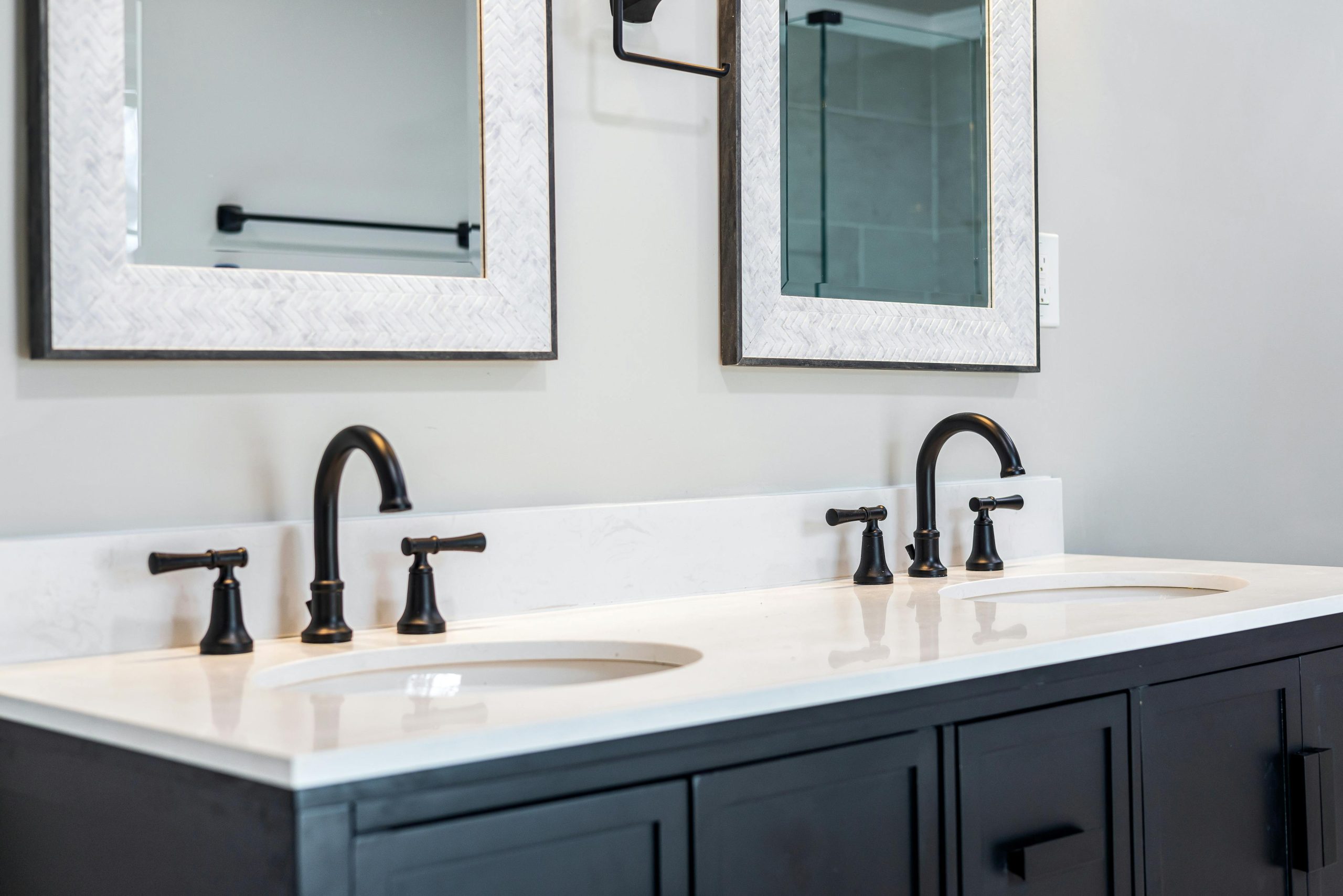 Sleek bathroom vanity featuring a double sink setup with stylish black faucets and framed mirrors.